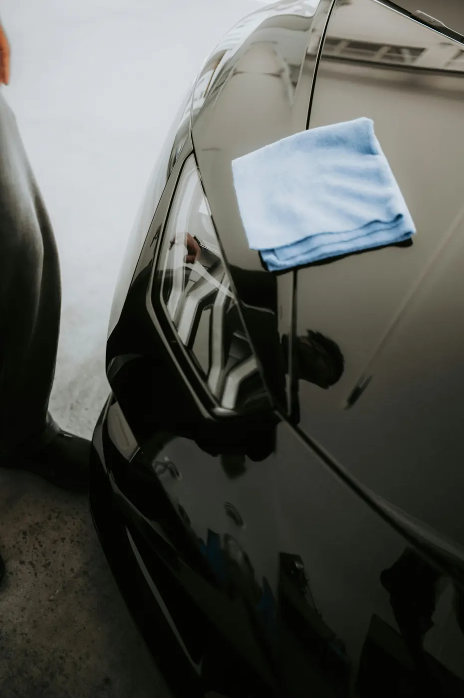 Final microfiber wipe-down on a freshly coated panel — careful hands, premium chemistry